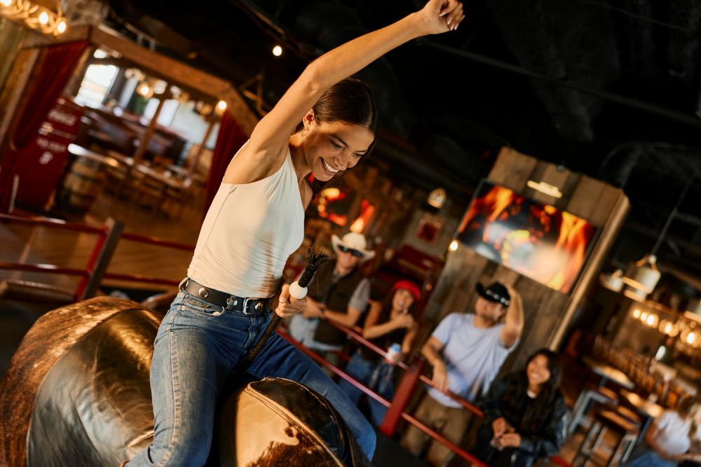 Woman riding a mechanical bull at Westwood Coast.