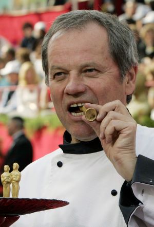 Photo of Wolfgang Puck biting a chocolate Oscar statuette.