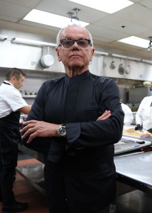 Photo of Wolfgang Puck dressed in black in a kitchen.