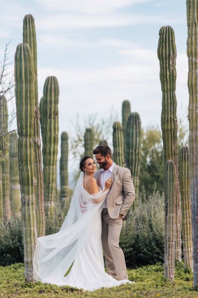Couple standing in front of cacti. 