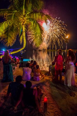 People sitting on the beach in Morada Bay watching fireworks