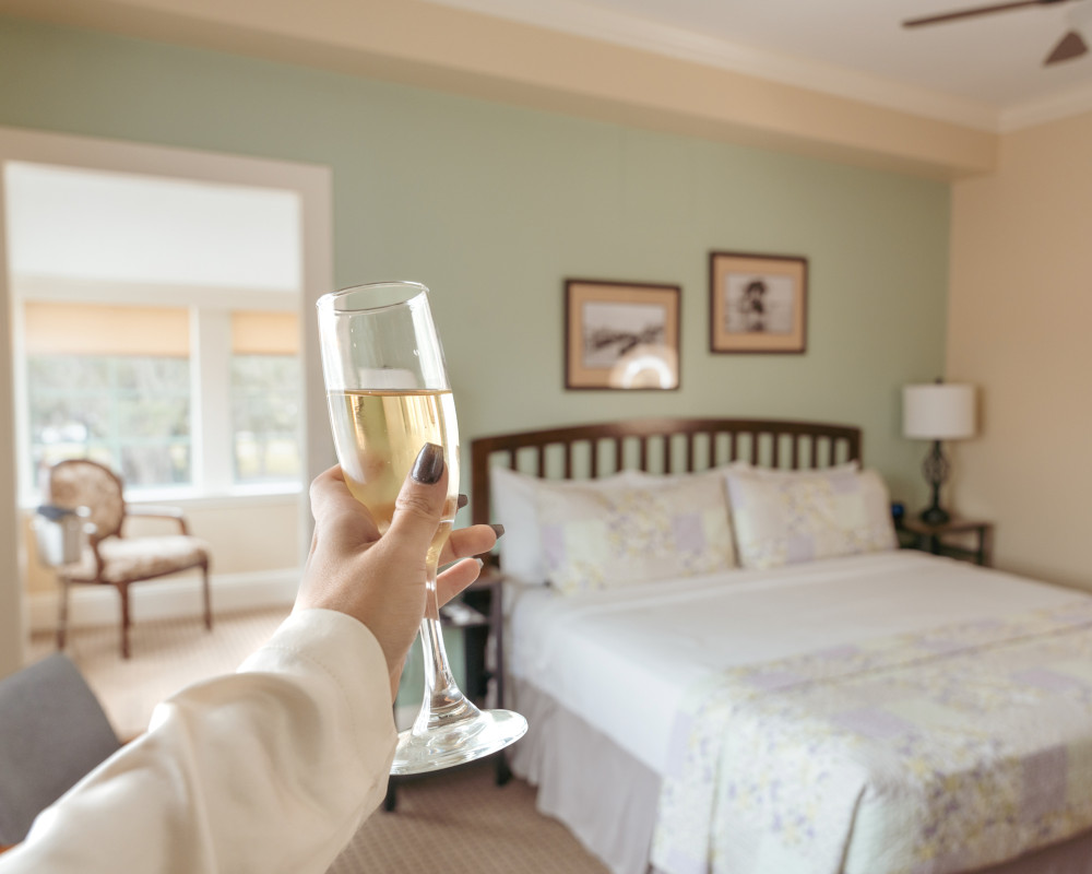 Guest holding a glass of champagne in a guest room of The Hacienda Hotel in New Port Richey