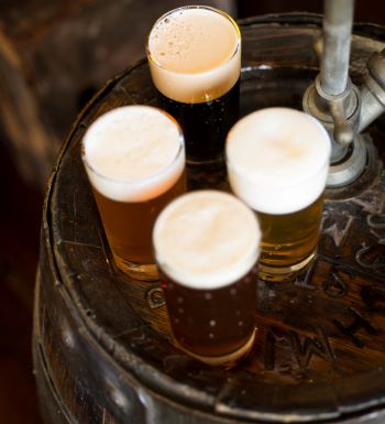 Four glasses of craft beer on top of barrel