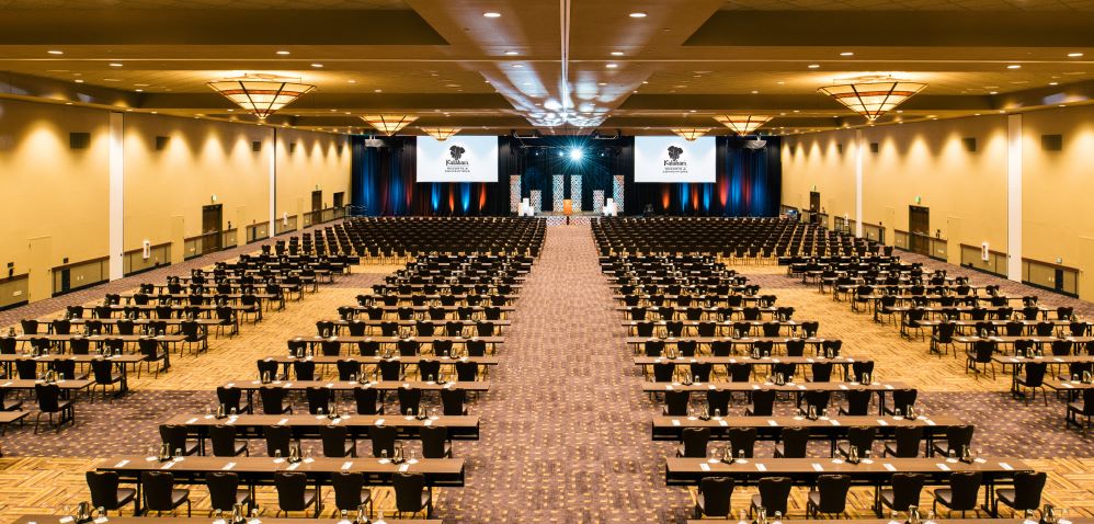 Large Meeting Space set up with long tables and chairs facing stage