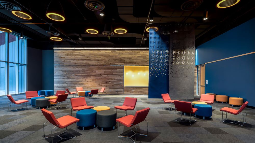 An interior meeting room with clusters of chairs and ottomans.