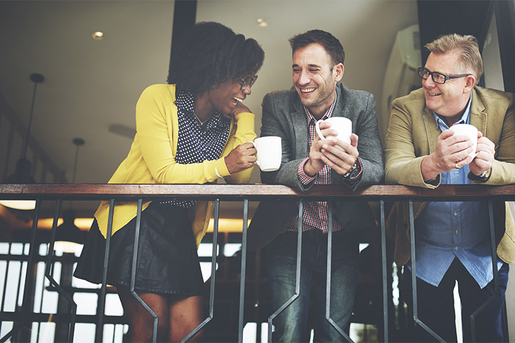 Three People Smiling and Engage in Conversation Over Railing