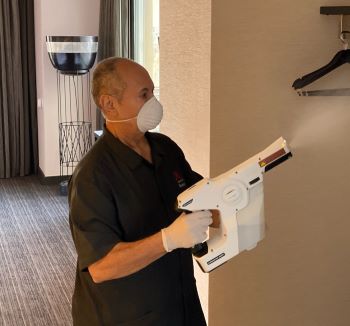 Man using electrostatic sprayer in guest room