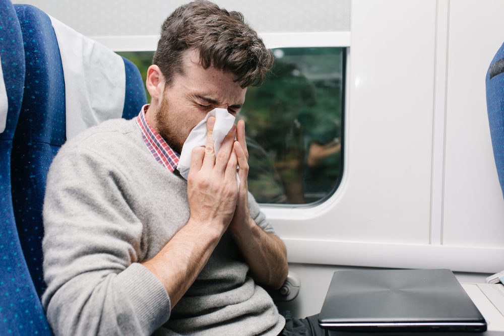 Man blowing nose on airplane.