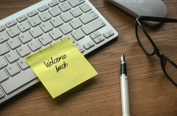 A graphic of a computer keyboard with a Post-It reading Welcome Back on it.