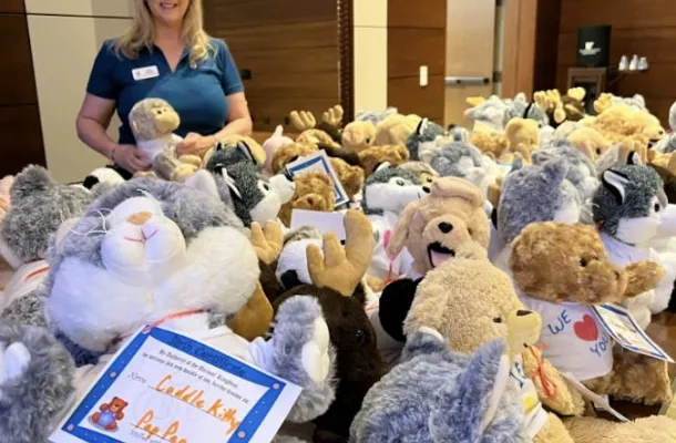 Woman standing with a bunch of stuffed animals for charity.