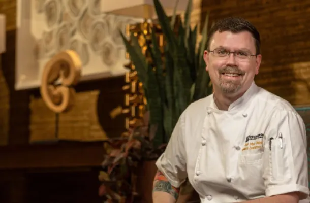 Chef Matthew Bishop sitting in a chair in his chef's uniform.
