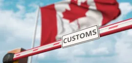 Canada's flag waves above a customs sign.