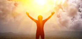 Image of person lifting arms with sun in the background.