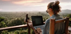 Photo of woman working on laptop outside.