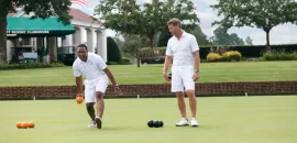 Image of two men lawnbowling at Pinehurst resort, in white shorts and teeshirts.