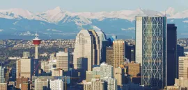 Photo of Calgary skyline with snow-capped mountains in the distance.