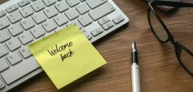 A graphic of a computer keyboard with a Post-It reading Welcome Back on it.