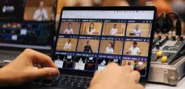 Image of two hands on a laptop, operating SlidesLive's NATE software system.