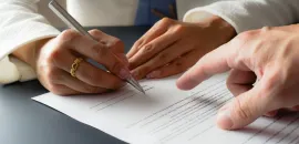 Image of two hands signing a legal contract.