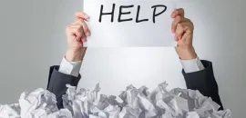 Image of a person holding a paper with the word HELP written on it, emerging from a bunch of crumpled up papers.
