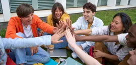image of young people sitting in a circle giving each other high fives.