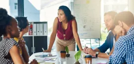 image of a woman leading a discussion at a small board table