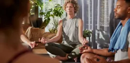 Photo of a woman and others meditating.