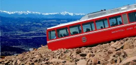 Pikes Peak Cog Railway train going up a mountain.