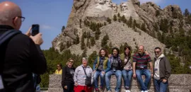 People posing for a photo in front of Mount Rushmore.