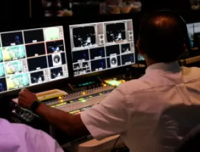 Man working audiovisual equipment for a hybrid meeting.