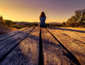 Image of woman sitting at the end of a dock.