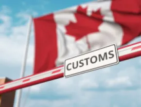 Canada's flag waves above a customs sign.