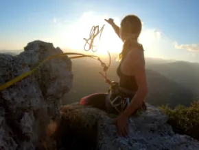 Woman climbing a cliff with a rope.