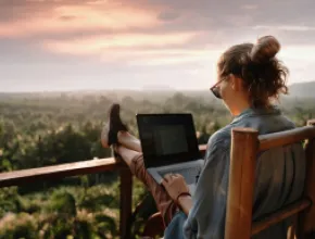 Photo of woman working on laptop outside.