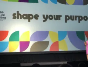 Photo of ASAE President and CEO Michelle Mason on stage at the association's annual conference, with the conference logo Shape Your Purpose on the screen behind her.