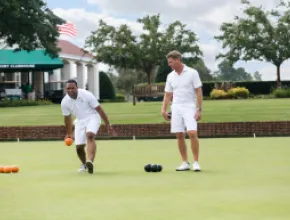 Image of two men lawnbowling at Pinehurst resort, in white shorts and teeshirts.