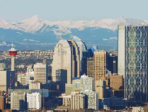 Photo of Calgary skyline with snow-capped mountains in the distance.