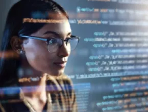 Image of woman looking at a computer screen with code passing by.