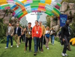 Photo of attendees attending Dreamforce 2024, walking under a rainbow-colored arch.