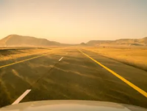 Photo of a road with sand blowing across it.