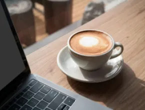 Cup of coffee on a table next to a laptop