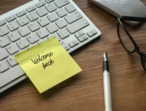 A graphic of a computer keyboard with a Post-It reading Welcome Back on it.