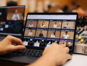 Image of two hands on a laptop, operating SlidesLive's NATE software system.