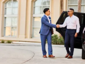Photo of a Gaylord Hotels Celebrity Services staff member greeting a guest as he exits a black SUV.