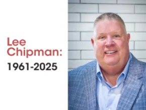 Photo of Lee Chipman in a blue blazer in front of a white brick background