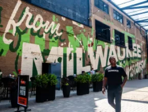 LeRoy Butler poses in front of a Milwaukee mural for Ask LeRoy. Credit: Visit Milwaukee