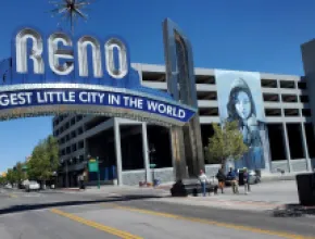 Photo Biggest Little City in the World sign with a mural on a parking garage on the right.