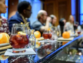 Photo of a cocktail on a bar with bar patrons behind it.