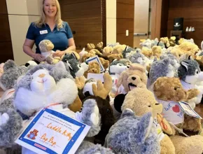 Woman standing with a bunch of stuffed animals for charity.