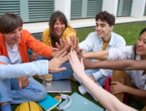 image of young people sitting in a circle giving each other high fives.